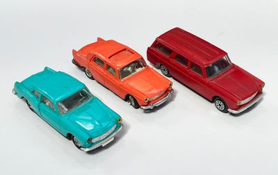 trois petites voitures sont alignées sur une surface blanche