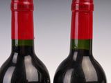 two bottles of red wine sitting next to each other on top of a table