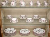 de nombreuses tasses et soucoupes sur les étagères du vaisselier
