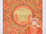 versa versa orange perfume bottle next to a box with a gold medallion on it