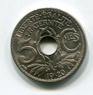 an old coin with a hole in the middle of it on a white surface