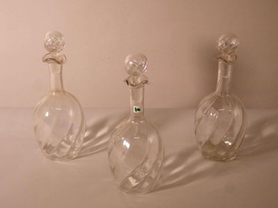 trois bouteilles en verre vides posées sur une surface blanche