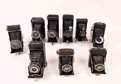 several old cameras are lined up in a row on a white surface