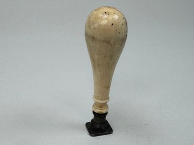 un petit vase blanc avec un socle noir posé sur une table
