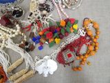 many different necklaces and bracelets laid out on a table
