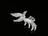 a close up of a bird brooch on a black surface