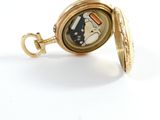a small gold pocket watch with a picture of a cat