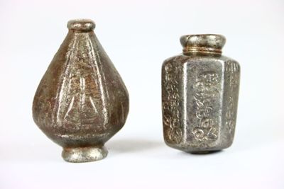 deux vases en argent posés l'un à côté de l'autre sur une surface blanche