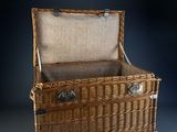 a wicker trunk that is open on a black background