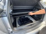 a man opening the trunk of a car with his foot in it