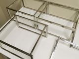 three glass and chrome trays on top of a white table