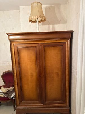 a wooden cabinet in the corner of a room with a lamp on top of it