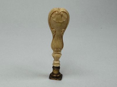 une petite cuillère en bois avec un manche, posée sur une surface blanche