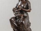 bronze statue of a woman holding a child on a wooden table
