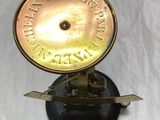 brass plated clock on a black stand with a white background