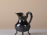 an image of a silver pitcher sitting on top of a white table