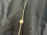 the back of a black dress with a gold button on it