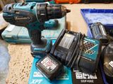 a cordless drill and two batteries sitting on a table