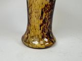 a brown and black vase sitting on a white surface