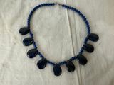 a necklace with blue beads and blue stones on a white cloth