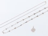 trois colliers en argent et un pendentif en argent sur fond blanc