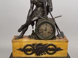 une photo représentant la statue d'un homme avec une horloge posée sur une table