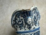 a blue and white vase with a face on it