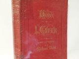 un vieux livre rouge posé sur une table blanche