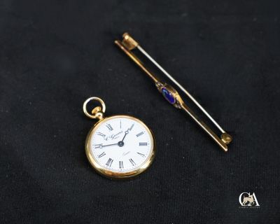 une montre de poche en or et une aiguille posée sur un tissu noir