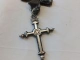 une croix en argent ornée d'un oiseau, posée sur une table blanche