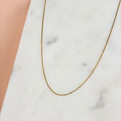 a gold chain necklace on a marble surface