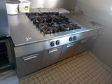 une plaque de cuisson en acier inoxydable dans une cuisine où se trouve un seau sur le plan de travail
