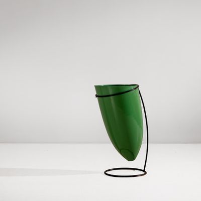 une lampe de table verte avec un fil noir posée sur une surface blanche