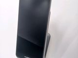 a black cell phone sitting on a stand on a white surface
