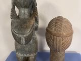 a statue of a woman holding a hat next to a vase