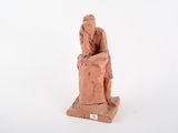 figurine représentant un homme assis sur une chaise, la main posée sur la tête