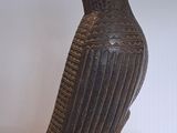 une statue représentant un oiseau perché sur un socle en bois