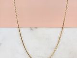 un collier à chaîne en or posé sur une surface en marbre
