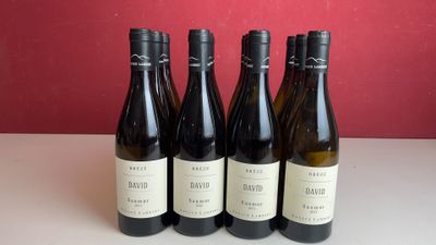Quatre bouteilles de vin sont posées sur une table devant un mur rouge.