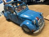 a blue toy car with people in it sitting on a table