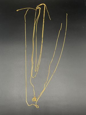 un collier en or composé d'une longue chaîne et orné d'une fleur