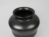 a black vase that is sitting on a white surface