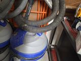 un aspirateur bleu et blanc posé à côté d'une pile d'autres aspirateurs