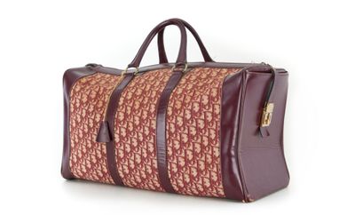 un sac de voyage marron et rouge posé sur une surface blanche