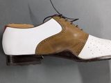 men ' s tan and white dress shoes on a gray surface