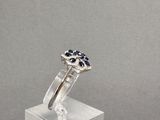 bague en argent sterling sertie de saphirs bleus et de diamants, posée sur un socle en acrylique transparent