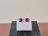 a pair of pink sapphire earrings sitting on top of a marble block