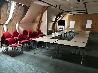 une pièce avec une longue table et des chaises rouges