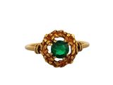 gros plan d'une bague en or avec une pierre verte