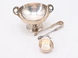 a silver bowl with a strainer and spoon next to it